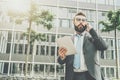 Young businessman in suit and tie is standing outdoor,holding tablet computer and talking on his cell phone Royalty Free Stock Photo