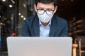 Young Businessman in suit wearing surgical face mask and using laptop, man typing keyboard computer notebook in office or cafe. Royalty Free Stock Photo