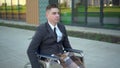 Young businessman in a suit in a wheelchair. A serious man is riding in a wheelchair against a business center. Special