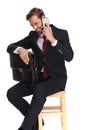 young businessman with suitcase sitting and laughing on the phone