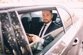 Young businessman talking on mobile phone and looking away while sitting on the back seat of a car Royalty Free Stock Photo