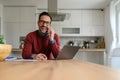 Young businessman talking over smart phone and laughing at camera while working in home office Royalty Free Stock Photo