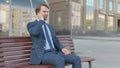 Businessman Talking on Phone while Sitting Outdoor on Bench Royalty Free Stock Photo