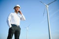 Young Businessman Talking to Manager Using Smart Telephone On Wind Turbine Field, Green Energy Concept