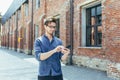 Young businessman uses phone outside office, happy and smiling man with smartphone Royalty Free Stock Photo