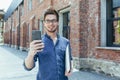 Young businessman uses phone outside office, happy and smiling man with smartphone Royalty Free Stock Photo