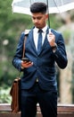 Nothing will damper his determination. a young businessman using a cellphone while holding an umbrella on a rainy day in Royalty Free Stock Photo