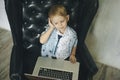 Young businessman using a laptop. funny child in glasses. Fashion portrait of little handsome boy in office Royalty Free Stock Photo