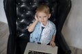 Young businessman using a laptop. funny child in glasses. Fashion portrait of little handsome boy in office Royalty Free Stock Photo