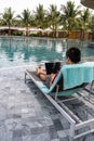 Young businessman using laptop at poolside on summer vacation Royalty Free Stock Photo