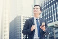 Young businessman using mobile phone while carrying bag in the city Royalty Free Stock Photo