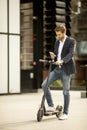 Young businessman using mobile phone  on electric scooter Royalty Free Stock Photo