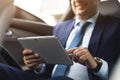 Young businessman using tablet pc while sitting on back seat of a car. Caucasian male business executive by a taxi and Royalty Free Stock Photo