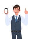 Young businessman in vest suit showing a blank screen mobile phone and pointing finger up. Person holding white display smartphone Royalty Free Stock Photo