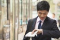 Young businessman waiting for the bus and checking his watch at the bus stop in Beijing, China