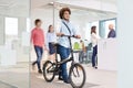 Young businessman walking with bicycle while colleagues in background at office Royalty Free Stock Photo