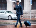 The man on a mission. a young businessman walking with a suitcase while holding an umbrella on a rainy day in the city. Royalty Free Stock Photo