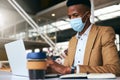 Young Businessman Wearing Mask Working On Laptop At Hot Desk In Office During Health Pandemic Royalty Free Stock Photo