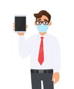 Young businessman wearing medical mask and showing tablet computer. Person with eye glasses holding digital pad. Healthy lifestyle Royalty Free Stock Photo