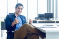 A young businessman wearing a suit and a long sleeve shirt inside and sitting smart poses has a feel happy smile in a modern