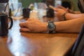 businessman wearing wrist watch on his arm. while staying in meeting room have ceramic glass and wooden work table are background Royalty Free Stock Photo