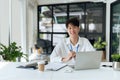 young businessman in white shirt sitting at desk holding pen and working on laptop. employee working at desk. look at Royalty Free Stock Photo