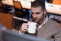 Young businessman working on computer in co work space. Coworking process, businessman working at modern office, drinking tea