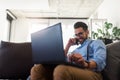 Young businessman working on laptop computer while sitting on sofa at home Royalty Free Stock Photo