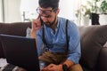 Young businessman working on laptop computer while sitting on sofa at home Royalty Free Stock Photo