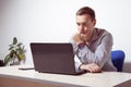 Young businessman working on laptop in office, being concerned. Toned in low rose Royalty Free Stock Photo