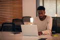 Young Businessman Working Late Sitting At Desk With Laptop In Modern Open Plan Office Royalty Free Stock Photo