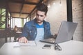 Young businessman working in office, sitting at desk, looking at laptop computer screen, smiling Royalty Free Stock Photo