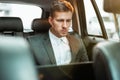 Young businessman works in his laptop while sitting in his car on his way to office, multitasking concept Royalty Free Stock Photo