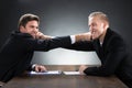 Young Businessmen Fighting At Wooden Desk