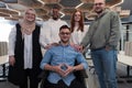 Young businessmen in a modern office extend a handshake to their business colleague in a wheelchair, showcasing Royalty Free Stock Photo