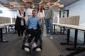 Young businessmen in a modern office extend a handshake to their business colleague in a wheelchair, showcasing