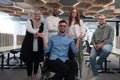 Young businessmen in a modern office extend a handshake to their business colleague in a wheelchair, showcasing