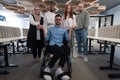 Young businessmen in a modern office extend a handshake to their business colleague in a wheelchair, showcasing