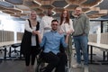 Young businessmen in a modern office extend a handshake to their business colleague in a wheelchair, showcasing Royalty Free Stock Photo