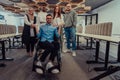 Young businessmen in a modern office extend a handshake to their business colleague in a wheelchair, showcasing