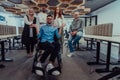 Young businessmen in a modern office extend a handshake to their business colleague in a wheelchair, showcasing Royalty Free Stock Photo