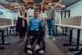 Young businessmen in a modern office extend a handshake to their business colleague in a wheelchair, showcasing Royalty Free Stock Photo