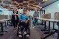 Young businessmen in a modern office extend a handshake to their business colleague in a wheelchair, showcasing Royalty Free Stock Photo