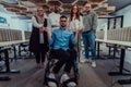 Young businessmen in a modern office extend a handshake to their business colleague in a wheelchair, showcasing Royalty Free Stock Photo
