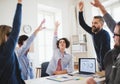 Young businesspeople sitting around table in a modern office, celebrating success. Royalty Free Stock Photo