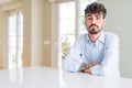 Young businesss man sitting on white table puffing cheeks with funny face