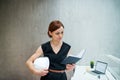 Young businesswoman or architect with diary and laptop standing in office. Royalty Free Stock Photo