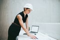 Young businesswoman or architect with helmet and laptop standing in office. Royalty Free Stock Photo