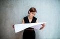 Young businesswoman or architect with blueprints standing in office. Royalty Free Stock Photo