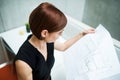 Young businesswoman or architect with blueprints standing in office. Royalty Free Stock Photo